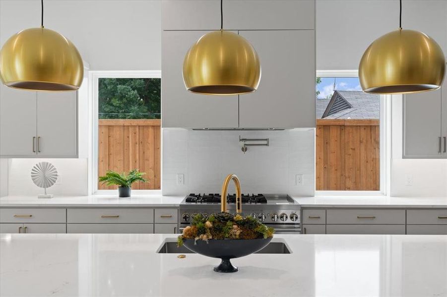 Kitchen featuring backsplash, gray cabinets, hanging light fixtures, and high end stainless steel range oven