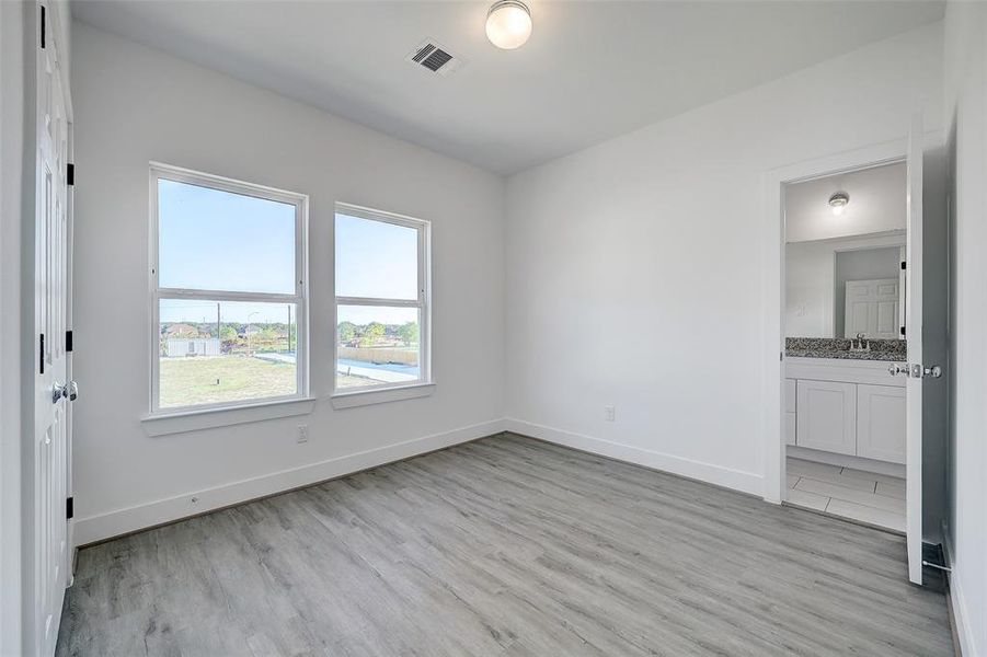 A sizable secondary bedroom offers durable LVP flooring, and direct access to an expansive jack and jill bathroom. Oversized windows allow the easy flow of natural light throughout the room.