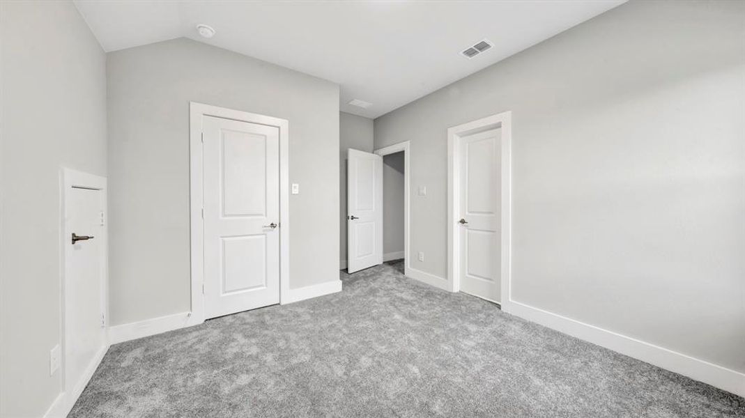 Unfurnished bedroom featuring light colored carpet and vaulted ceiling