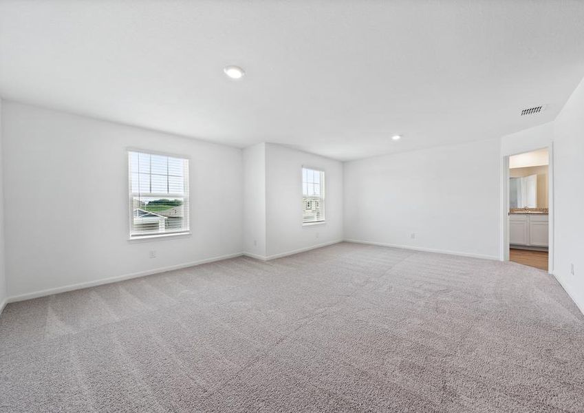 Expansive master bedroom with windows that create a bright, open space.