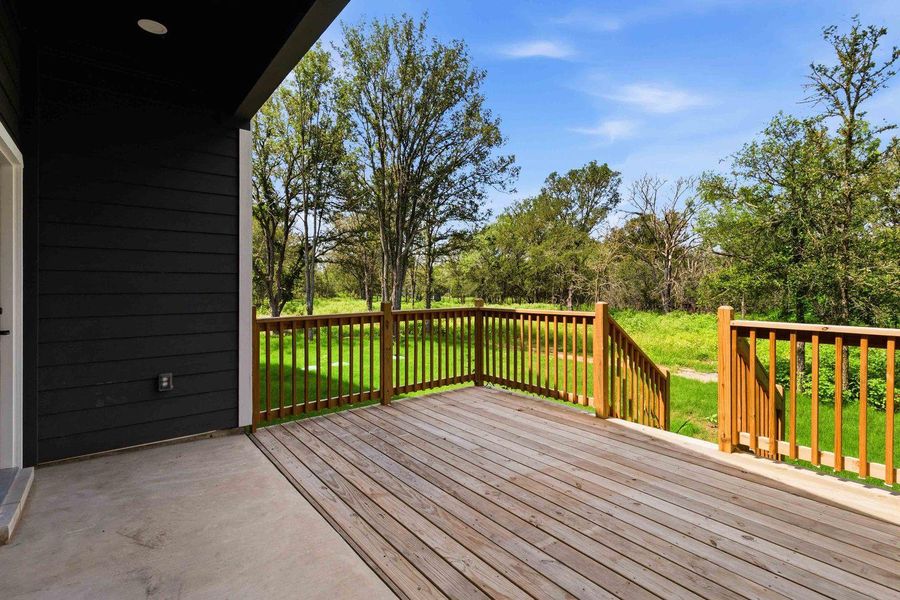 A spacious wooden deck extends to a natural landscape with mature trees and verdant growth. A spacious wooden deck extends to a natural landscape with mature trees and verdant growth.