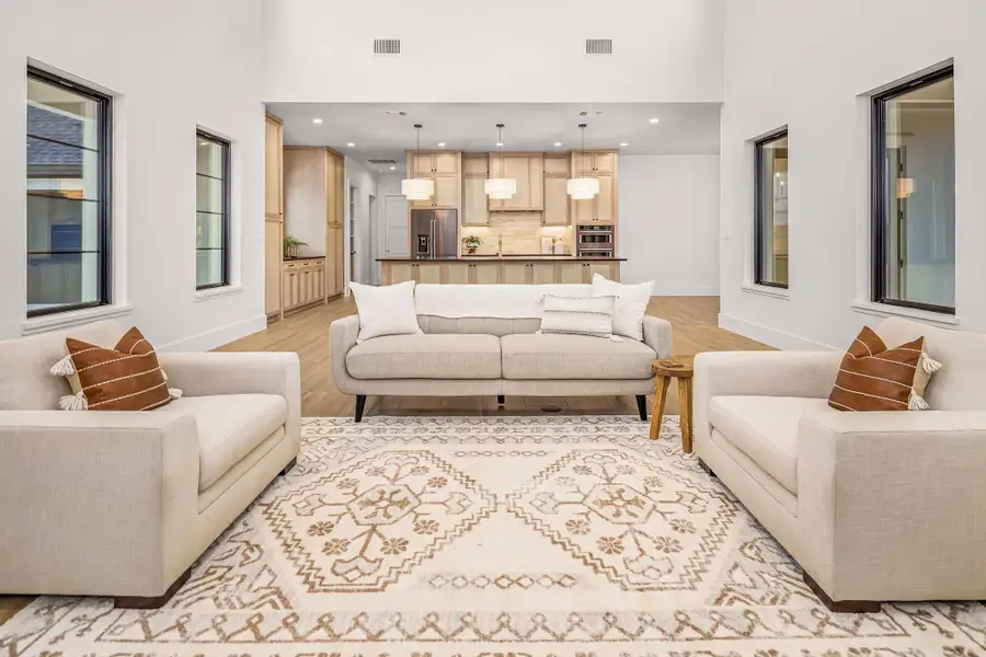 Living area featuring light wood finished floors, a towering ceiling, visible vents, and baseboards