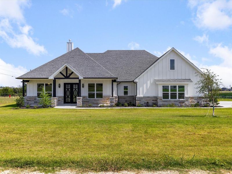 View of front of house featuring board and batten siding, a shingled roof, a front lawn, and stone siding View of front of house featuring board and batten siding, a shingled roof, a front lawn, and stone siding