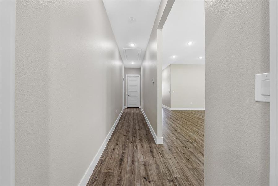 Corridor with attic access, wood finished floors, recessed lighting, and a textured wall Corridor with attic access, wood finished floors, recessed lighting, and a textured wall