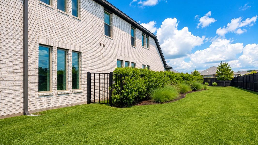 The exterior showcases white brick siding, dark gutters, and a black metal fence with a built-in gate.