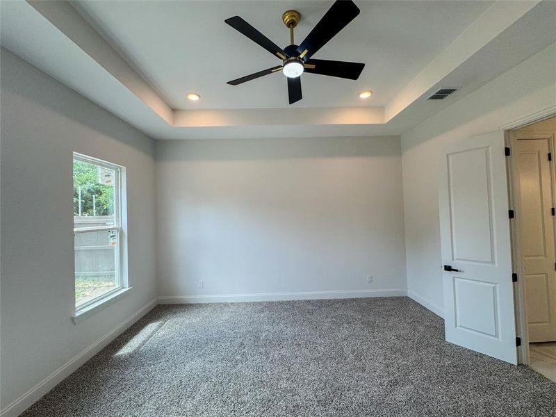 Spare room with carpet, a ceiling fan, baseboards, recessed lighting, and a tray ceiling Spare room with carpet, a ceiling fan, baseboards, recessed lighting, and a tray ceiling