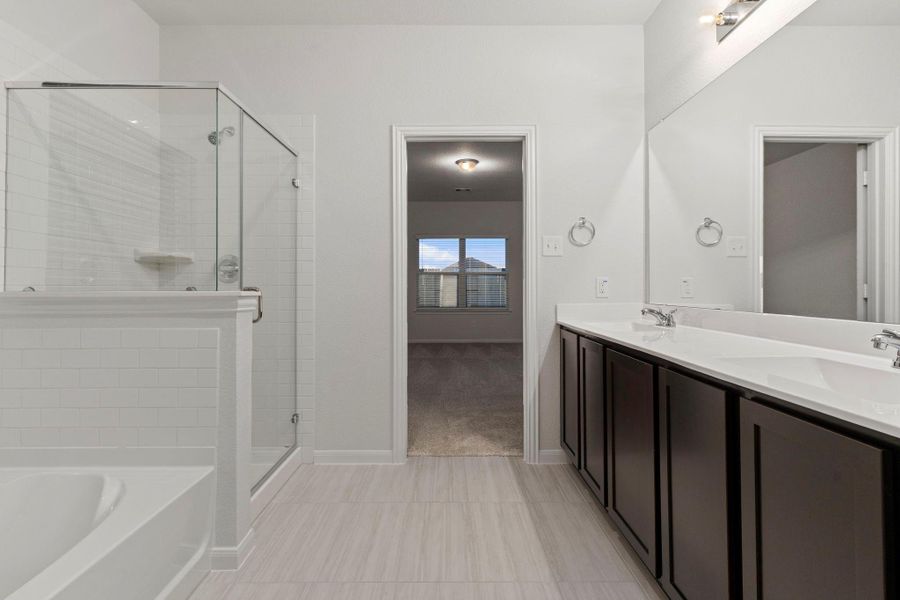 The primary bathroom continues to impress with dual sinks, extended counter space, and sleek cabinetry offering both beauty and functionality. Perfectly designed to make mornings easy and evenings relaxing.