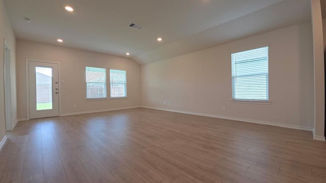 Spacious open-concept room featuring light wood-finish flooring and neutral wall tones Spacious open-concept room featuring light wood-finish flooring and neutral wall tones