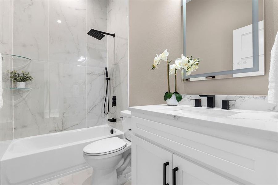 Full bathroom with vanity, tiled shower / bath combo, and toilet