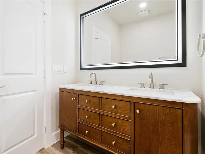 Double vanity featuring a wood-finish cabinet with brass hardware, a white countertop, and dual sinks Double vanity featuring a wood-finish cabinet with brass hardware, a white countertop, and dual sinks