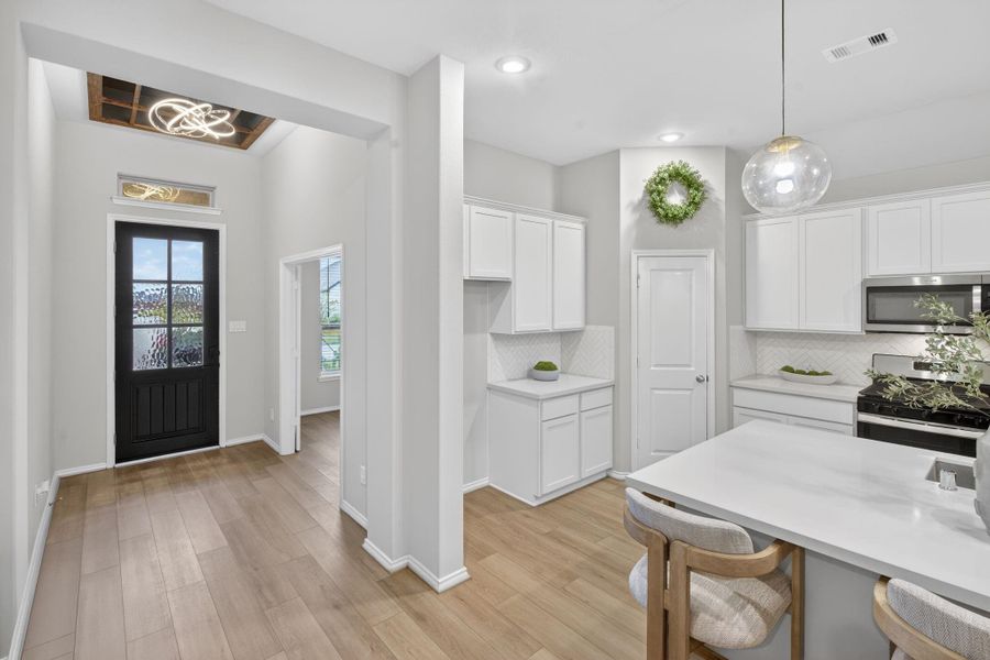 This photo showcases a modern kitchen with white cabinetry, built-in microwave, walk-in pantry, and a bright, open layout. The space features a stylish and convenient island with seating. This photo showcases a modern kitchen with white cabinetry, built-in microwave, walk-in pantry, and a bright, open layout. The space features a stylish and convenient island with seating.