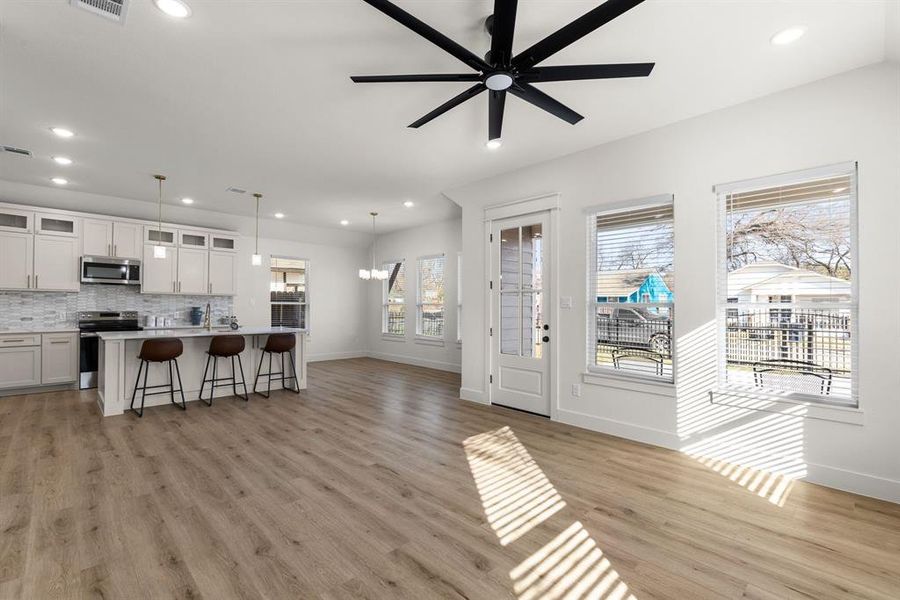 Living room featuring ceiling fan with notable chandelier and light hardwood / wood-style flooring