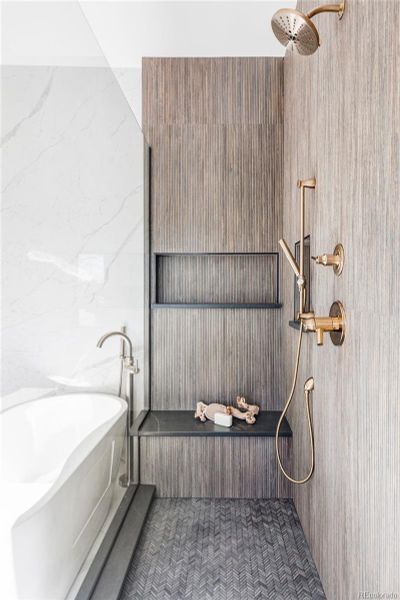 Primary suite shower is loaded with texture and comfort