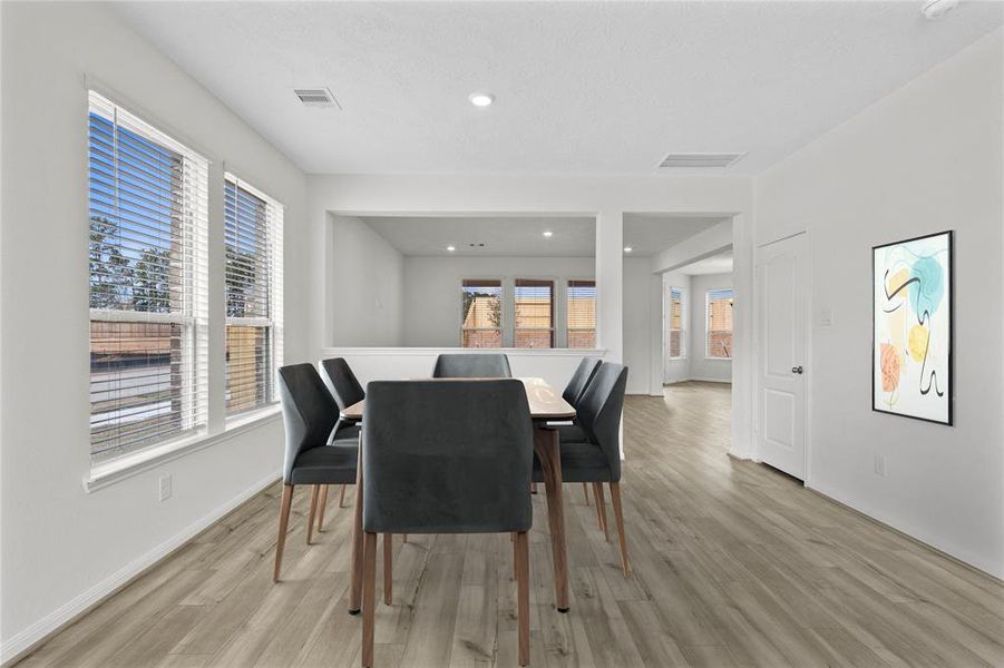 This formal dining area features high ceilings, recessed lighting, large windows with privacy blinds, and vinyl plank flooring!