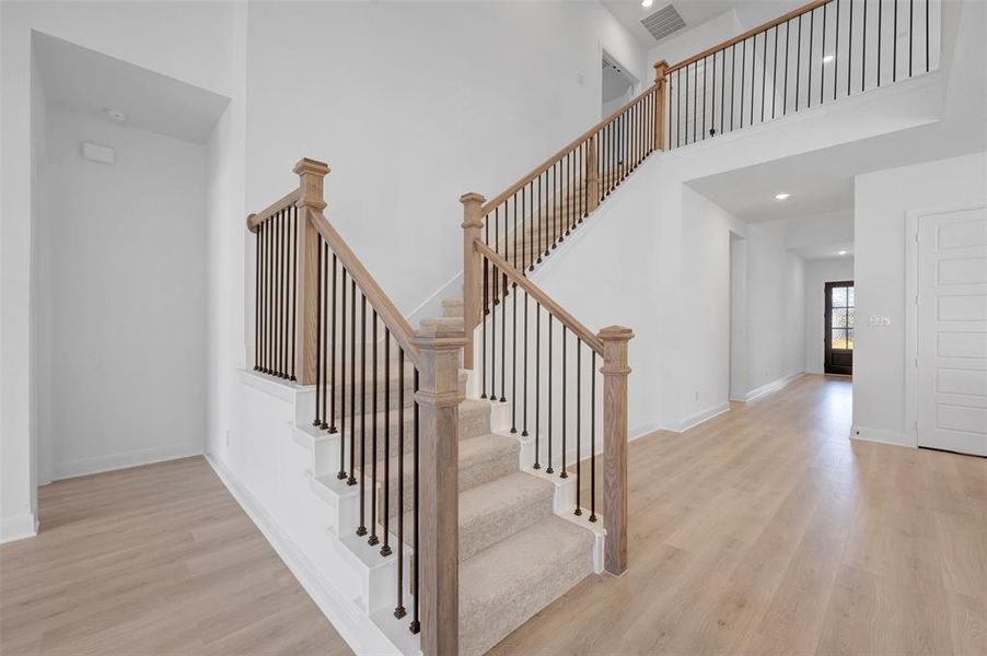 Staircase with wood finished floors, a high ceiling, and recessed lighting