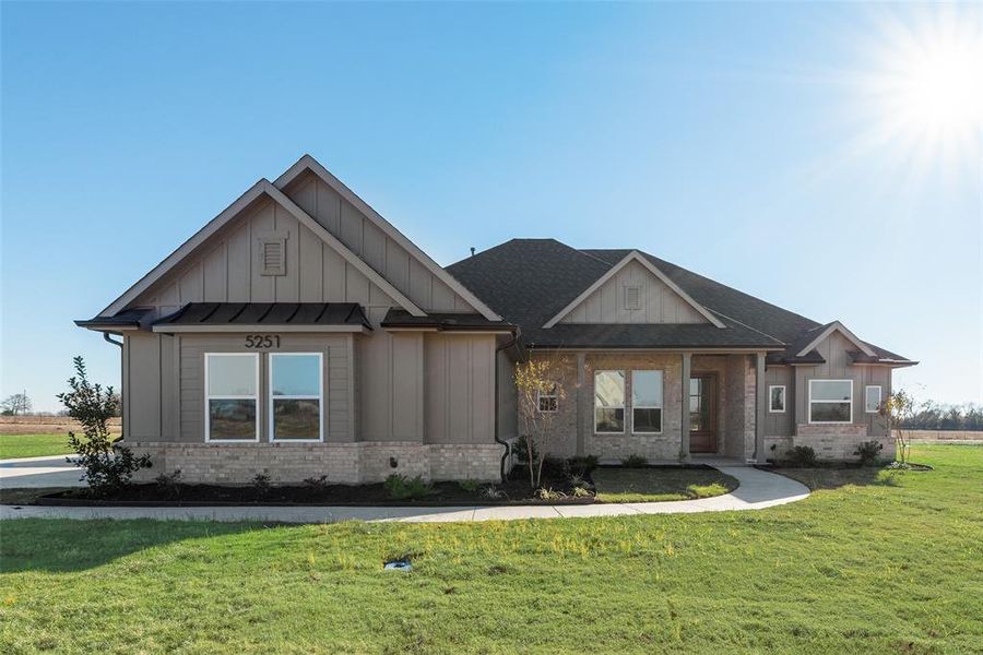 Craftsman-style house with brick siding, a front lawn, and board and batten siding Craftsman-style house with brick siding, a front lawn, and board and batten siding