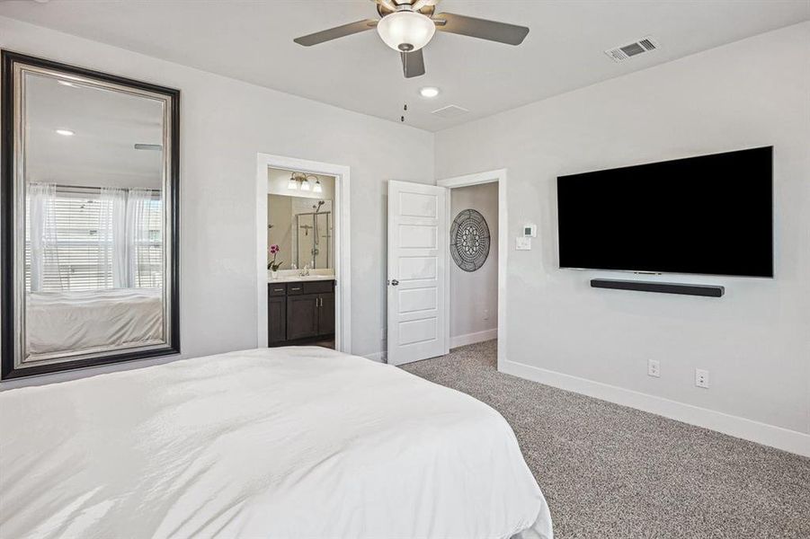 Bedroom with light carpet, ensuite bath, and ceiling fan