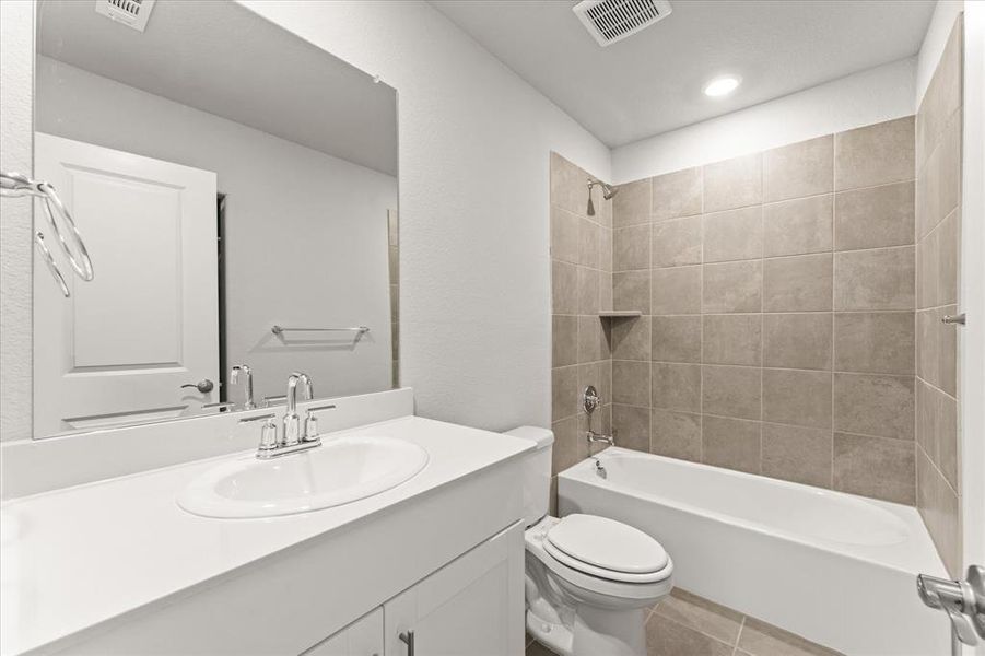 Full bathroom featuring vanity, toilet, tile patterned floors, and tiled shower / bath