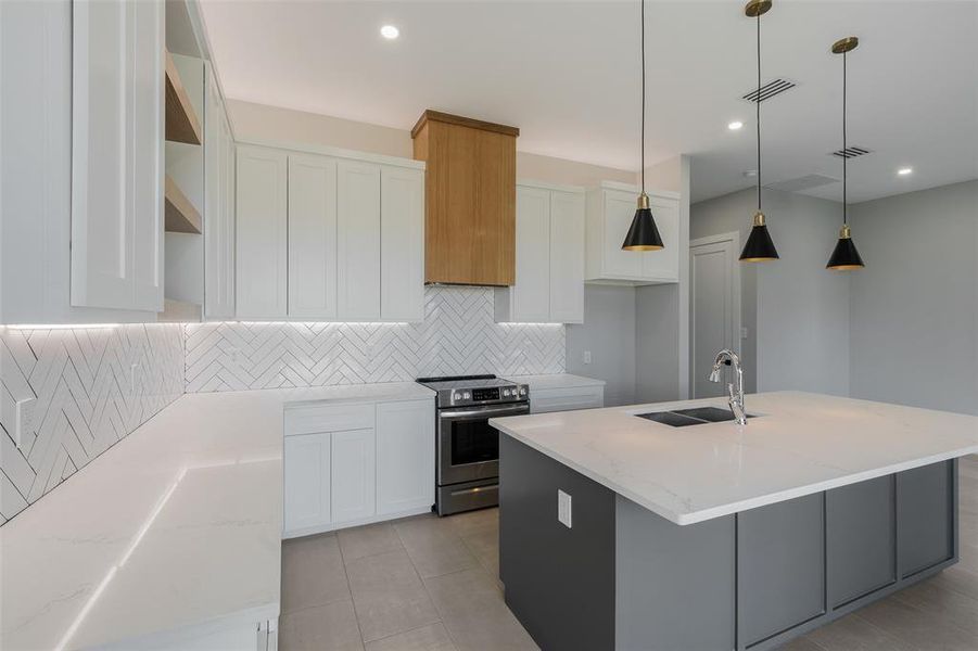 Kitchen featuring light stone countertops, white cabinetry, sink, and an island with sink