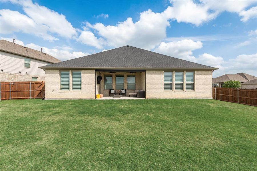 Expansive backyard featuring a large green lawn and a covered patio area