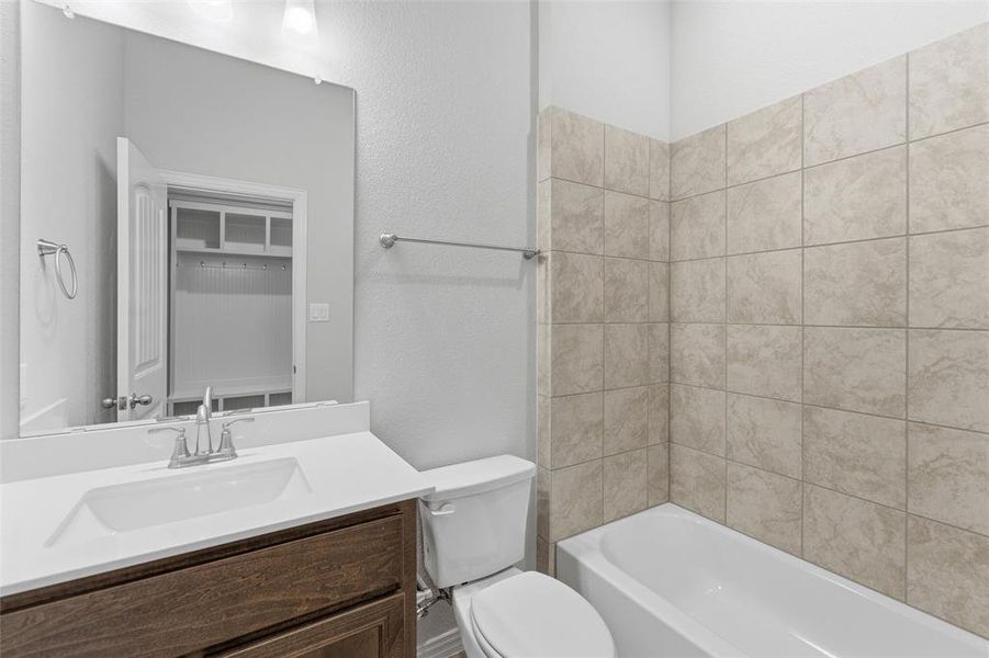Full bath with vanity, a textured wall, and tub / shower combination