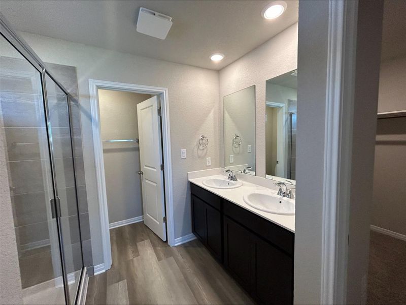 Full bath with a stall shower, wood finished floors, double vanity, and a spacious closet Full bath with a stall shower, wood finished floors, double vanity, and a spacious closet
