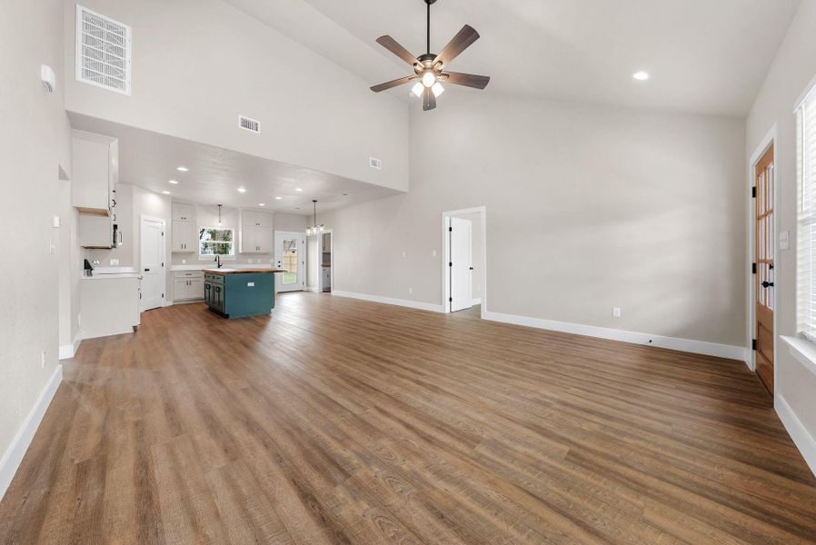 Unfurnished living room featuring recessed lighting, a ceiling fan, light wood-style floors, and a high ceiling