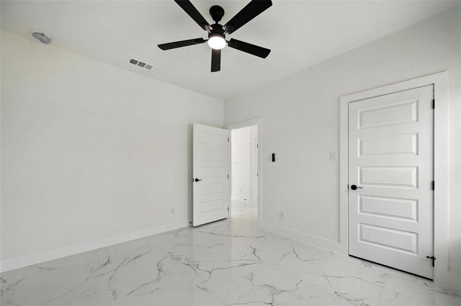 Unfurnished bedroom with light marble finish floors and ceiling fan