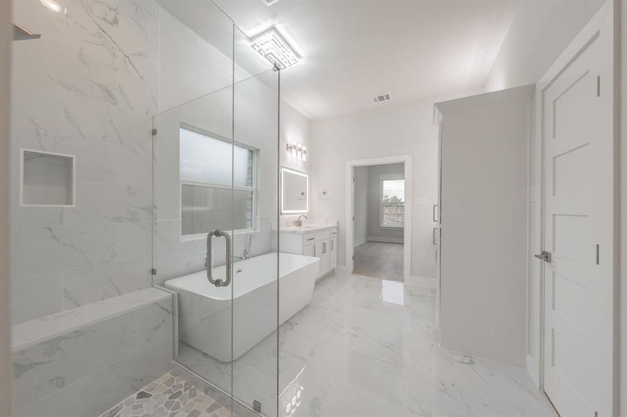 Bathroom featuring vanity, a freestanding bath, light marble finish flooring, and a marble finish shower