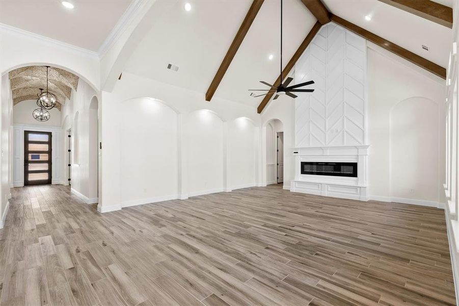 living room featuring ceiling fan with notable chandelier, high vaulted ceiling, custom flooring, and a fireplace