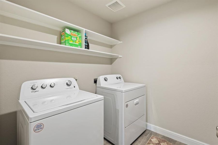 Dedicated laundry space featuring white shelving, light-toned walls, and patterned floor tile Dedicated laundry space featuring white shelving, light-toned walls, and patterned floor tile