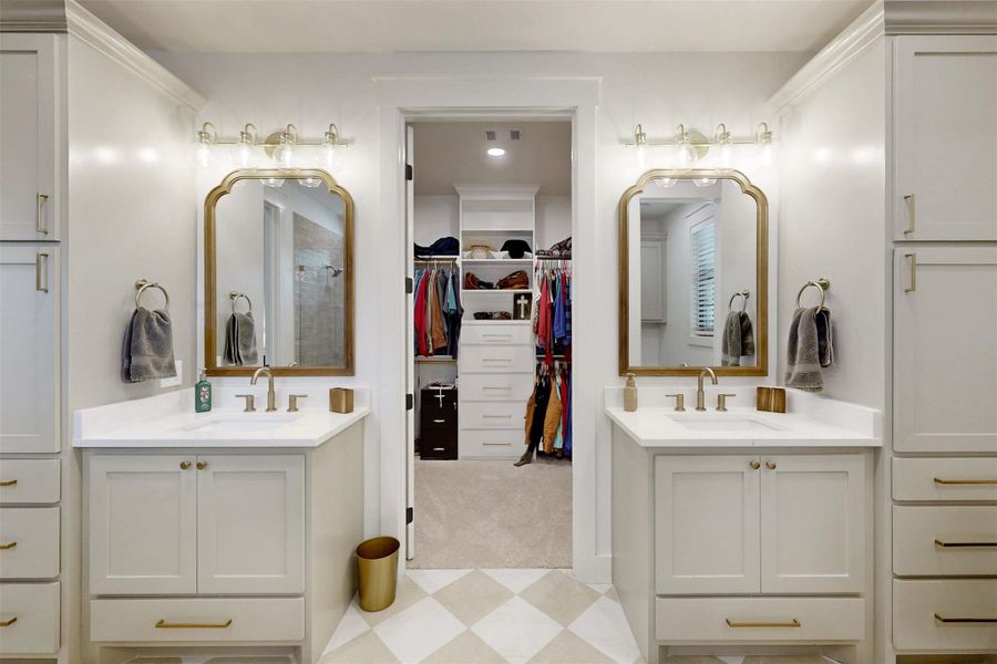 Full bath featuring two vanities, a walk in closet, and a shower