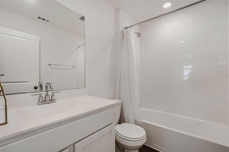 Second full upstairs Bathroom featuring a white vanity with an integrated sink, chrome faucet, and a large wall-mounted mirror Second full upstairs Bathroom featuring a white vanity with an integrated sink, chrome faucet, and a large wall-mounted mirror