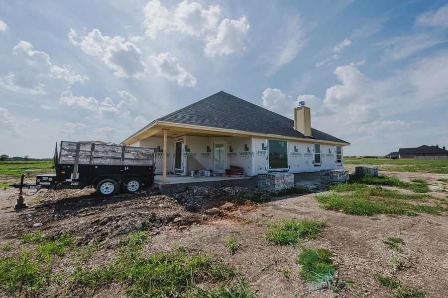 Rear view of house with a chimney, roof with shingles, and a patio area Rear view of house with a chimney, roof with shingles, and a patio area