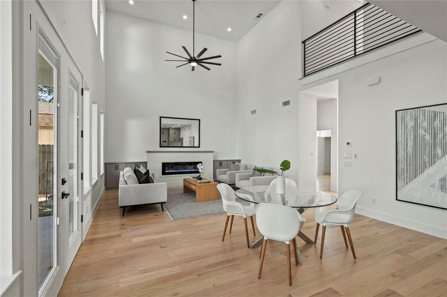 Dining room with plenty of natural light, ceiling fan, a towering ceiling, and light wood-type flooring