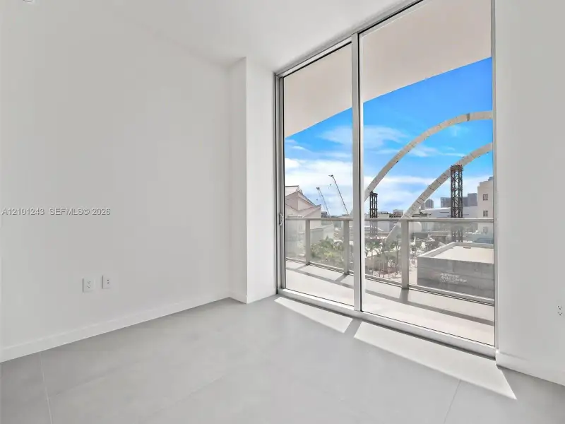 Floor-to-ceiling sliding glass doors, large format tile flooring, and a private balcony with a metal railing Floor-to-ceiling sliding glass doors, large format tile flooring, and a private balcony with a metal railing