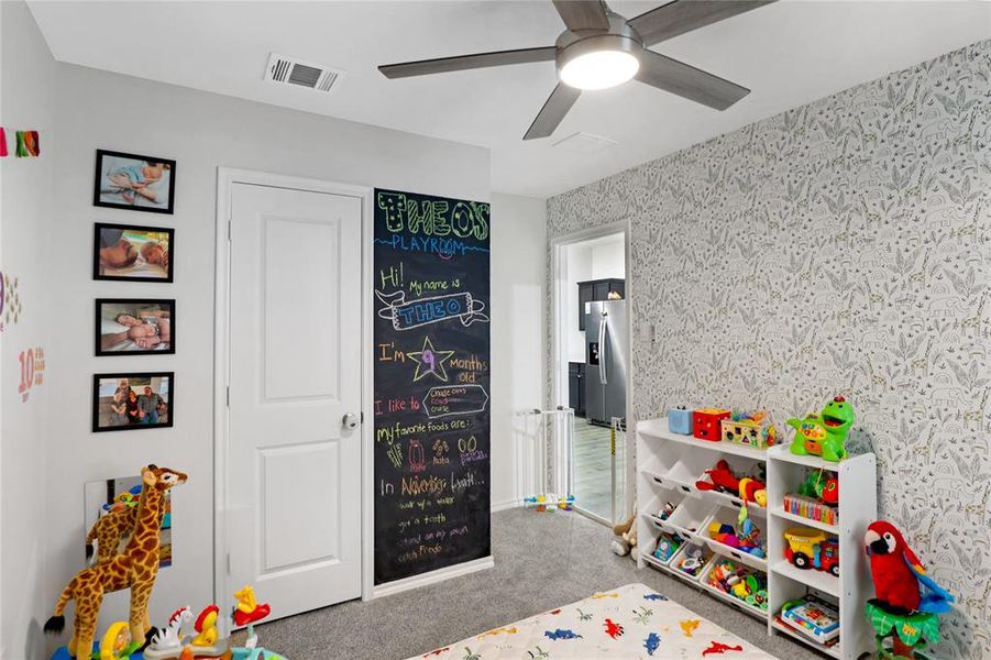 Recreation room with carpet floors, a ceiling fan, and wallpapered walls