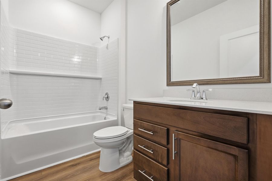 Bathroom featuring vanity, shower / tub combination, and dark wood-type flooring