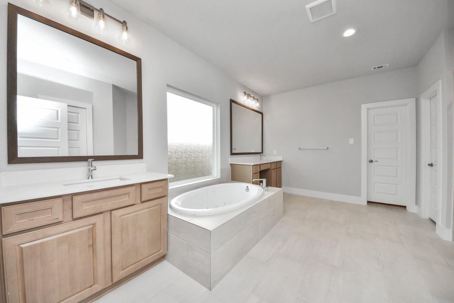 Elevate your daily routine at the elegant vanity, now equipped with double sinks, light countertops, modern hardware, and beautiful vanity lights.