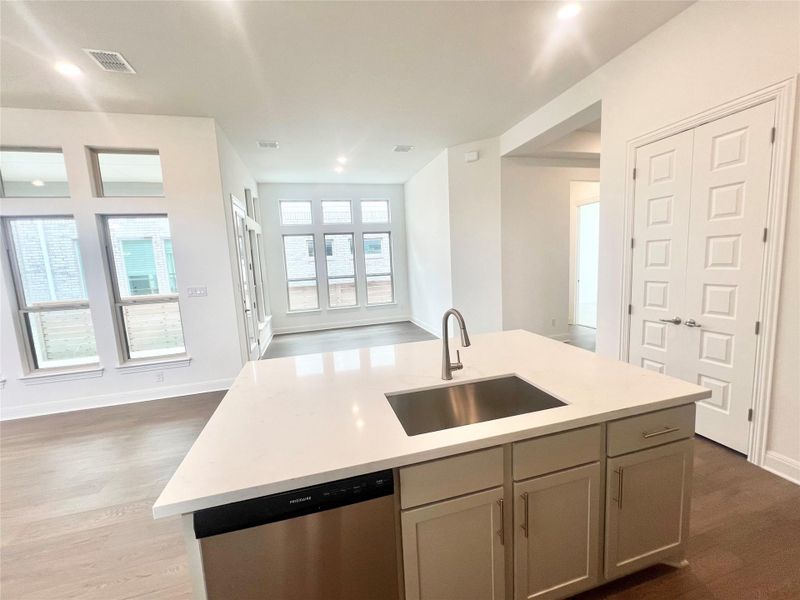 Kitchen with stainless steel dishwasher, dark wood-style floors, light countertops, open floor plan, and recessed lighting Kitchen with stainless steel dishwasher, dark wood-style floors, light countertops, open floor plan, and recessed lighting