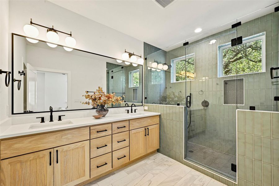 Spa-inspired primary bath with designer tile, frameless glass shower, dual vanities, and black fixtures. Spa-inspired primary bath with designer tile, frameless glass shower, dual vanities, and black fixtures.