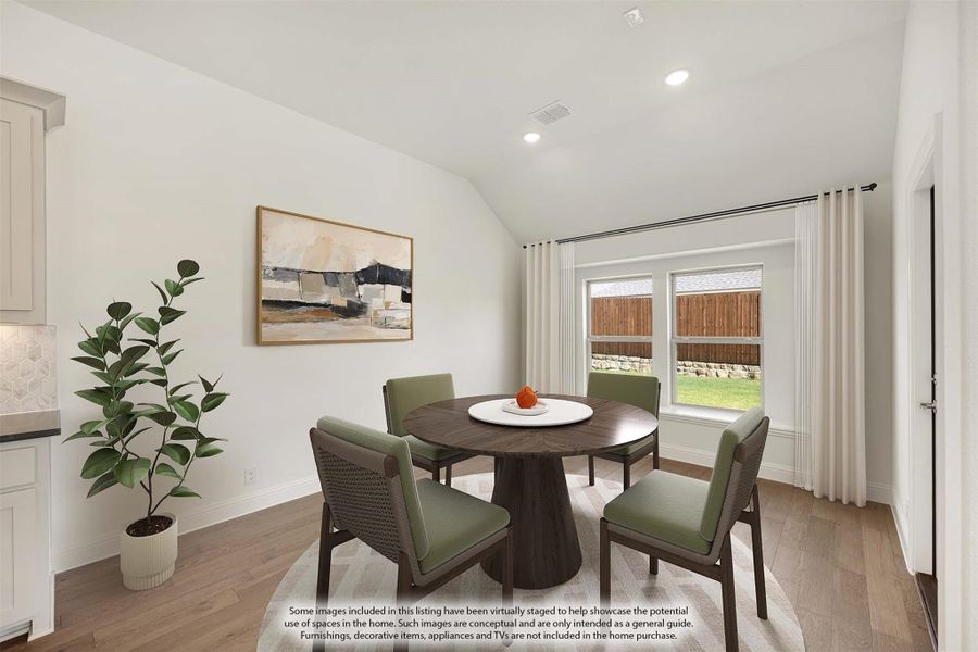 Dining area with round wood table, four green chairs, vaulted ceiling, and hardwood floors near a window