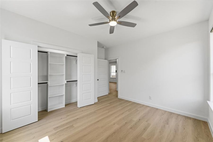 Bedroom featuring light wood-finish flooring, white walls, and a contemporary ceiling fan with integrated lighting