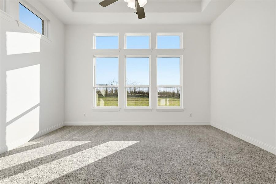 Spare room with ceiling fan, light colored carpet, a raised ceiling, and a water view Spare room with ceiling fan, light colored carpet, a raised ceiling, and a water view