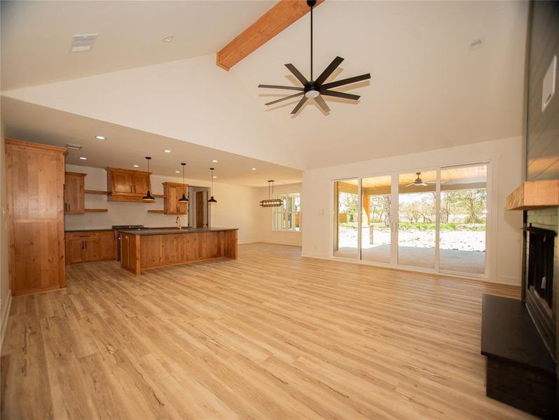 Living area featuring high vaulted ceiling, light wood-style flooring, ceiling fan, recessed lighting, and beam ceiling Living area featuring high vaulted ceiling, light wood-style flooring, ceiling fan, recessed lighting, and beam ceiling
