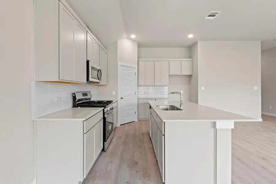 A well-appointed kitchen features a central island, modern appliances, and ample cabinetry for storage.
