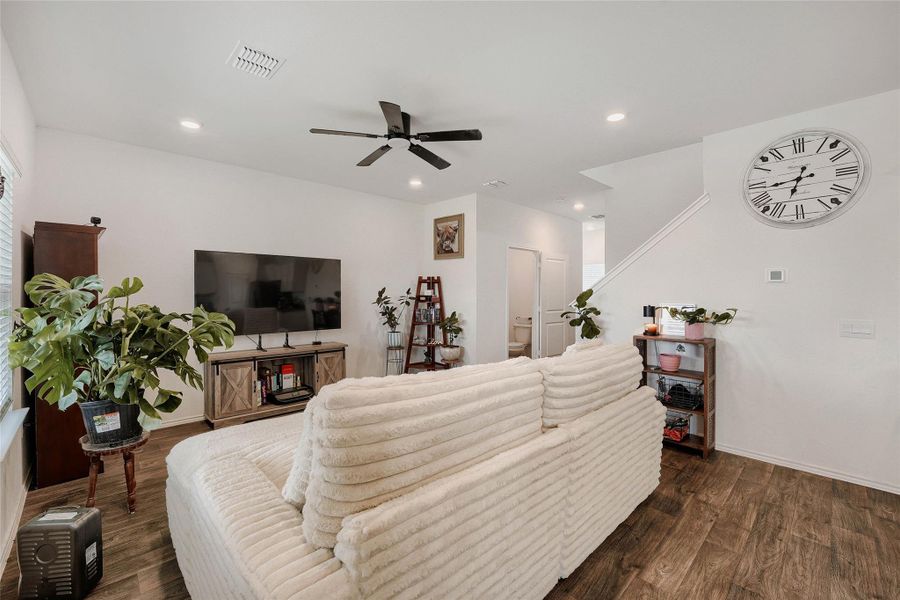 Spacious living area featuring wood-finish flooring, recessed lighting, and a ceiling fan Spacious living area featuring wood-finish flooring, recessed lighting, and a ceiling fan