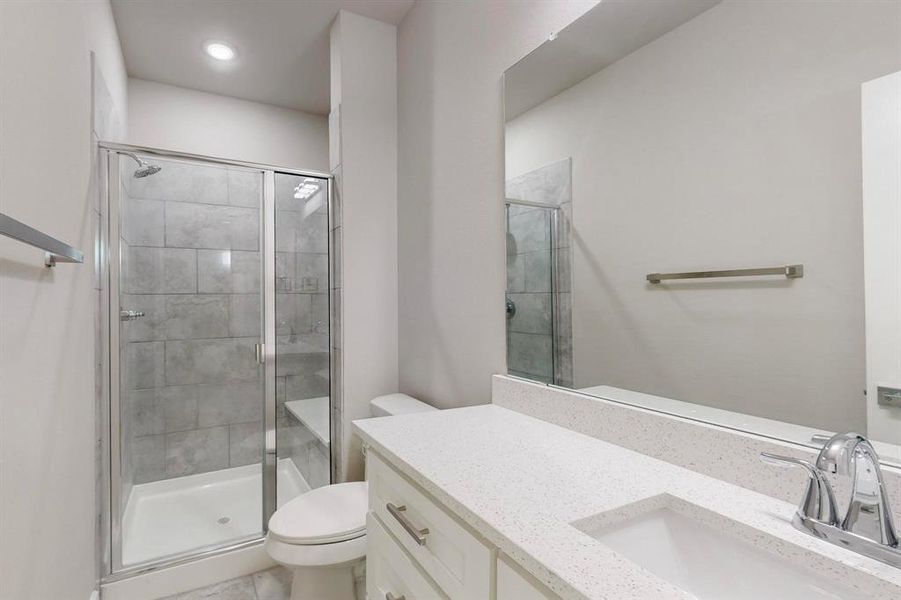 Bathroom with vanity, an enclosed shower, and toilet