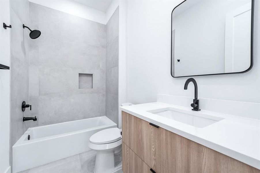 Elegant designer bathroom featuring a luxurious deep soaking tub, sleek solid cabinetry, and an eco-friendly dual-flush toilet.