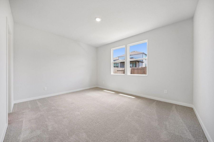 A well-lit bedroom features plush carpeting and multiple windows. A well-lit bedroom features plush carpeting and multiple windows.